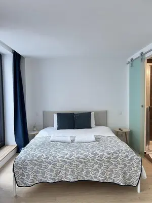 a bedroom with a large bed with blue curtains at Modern & Elegant Apartment near Montgomery in Brussels
