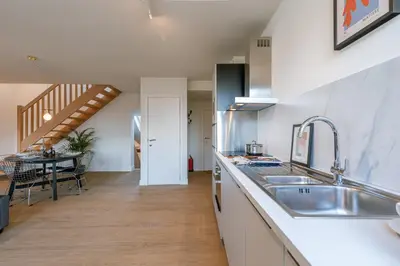 a kitchen with a sink and a dining table at Bright Duplex near Antwerp Cathedral in Antwerp
