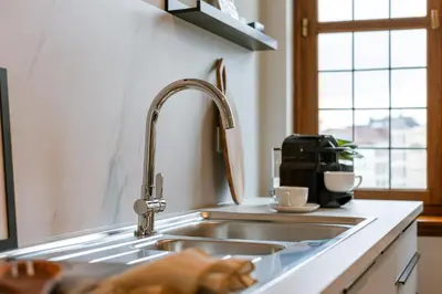 a kitchen sink with a faucet and two cups at Bright Duplex near Antwerp Cathedral in Antwerp