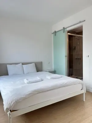 a white bed in a bedroom with a glass shower at Chic & Bright near Montgomery in Brussels