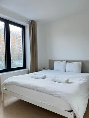 a white bed in a room with two windows at Chic & Bright near Montgomery in Brussels