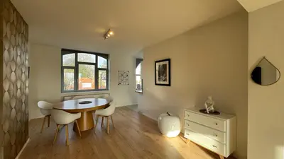 a dining room with a table and chairs and a window at Chez Pomme in Brussels