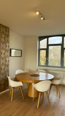 a dining room with a wooden table and white chairs at Chez Pomme in Brussels