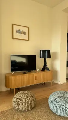a living room with a television and a table with a lamp at Chez Pomme in Brussels
