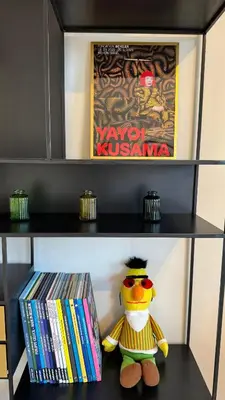 a stuffed toy sitting on a shelf with dvds at Chez Pomme in Brussels