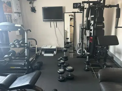 a room with a gym with machines and a tv at Steves Place Haasdonk in Beveren