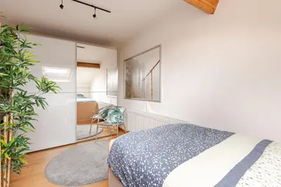 a bedroom with white walls and a bed and a plant at Steves Place Haasdonk in Beveren