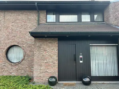 a brick house with a black door and two windows at Steves Place Haasdonk in Beveren