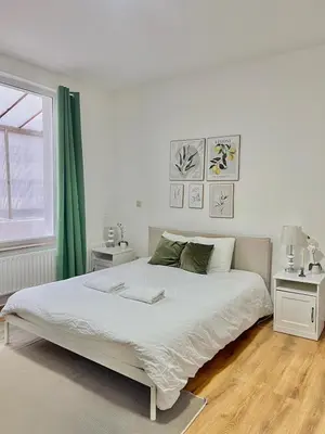 a white bedroom with a large bed and two tables at Spacious Apartment for 6 near Center of Brussels in Brussels