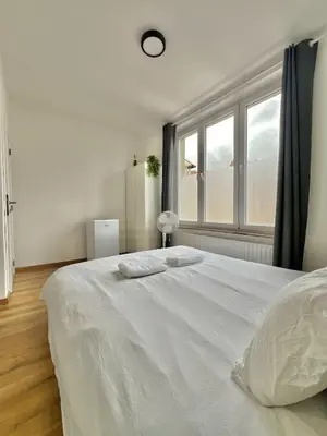 a white bed in a room with a window at Spacious Apartment for 6 near Center of Brussels in Brussels