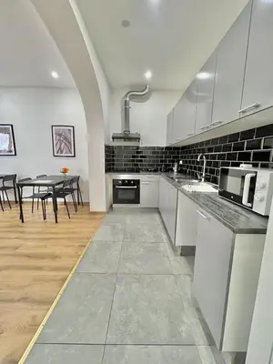 a kitchen with white cabinets and a table with chairs at Spacious Apartment for 6 near Center of Brussels in Brussels