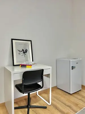 a white desk with a chair next to a refrigerator at Spacious Apartment for 6 near Center of Brussels in Brussels