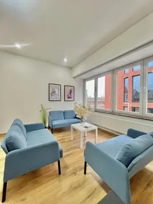 a living room with blue couches and windows at Spacious Apartment for 6 near Center of Brussels in Brussels