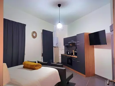 a bedroom with a bed and a kitchen with a tv at La Perla Appartements Louise RDC in Brussels