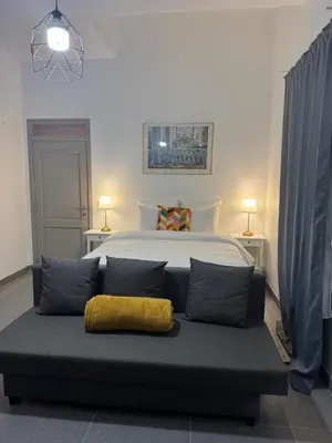 a bedroom with a bed and a couch with a yellow pillow at La Perla Appartements Louise RDC in Brussels
