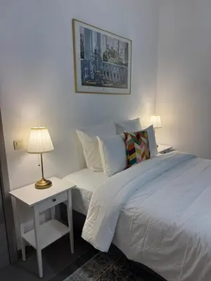 a bedroom with a bed and a table with a lamp at La Perla Appartements Louise RDC in Brussels