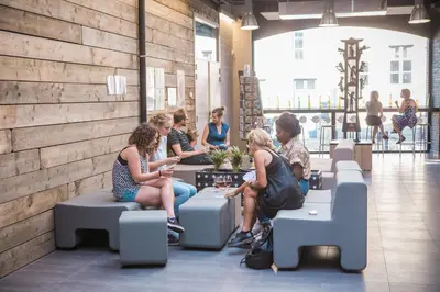 a group of people sitting on benches in a building at De Draecke Hostel in Ghent