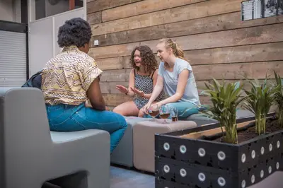 a group of three women sitting on a wall at De Draecke Hostel in Ghent