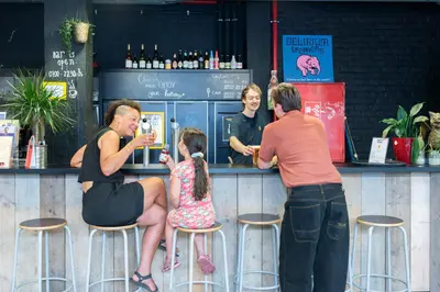 a group of people standing at a bar at De Draecke Hostel in Ghent