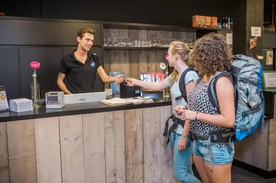 a man and two women standing at a counter at De Draecke Hostel in Ghent