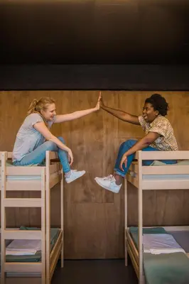 two girls sitting on top of bunk beds at De Draecke Hostel in Ghent