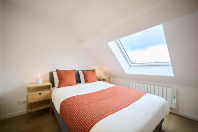a bedroom with a bed with orange pillows and a window at Appartement Ceuppens 5 in Brussels