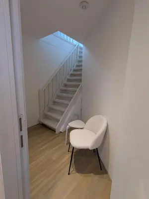 a room with a white chair and a staircase at upper st in Brussels