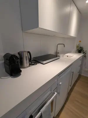 a white kitchen with a sink and a counter top at cozy nest basement st gilles in Brussels