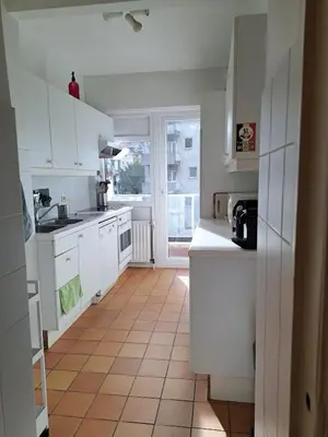 a kitchen with white cabinets and a tile floor at Bright and cosy apartment in Bruxelles in Brussels