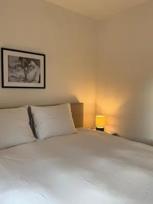 a bedroom with a bed with white sheets and a lamp at L'Excelsior Suites in Brasschaat