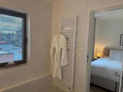 a robe is hanging on a rack in a bathroom at L'Excelsior Suites in Brasschaat