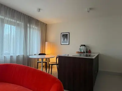 a living room with a red chair and a table at L'Excelsior Suites in Brasschaat