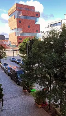 a tall building with cars parked in a parking lot at Luxury apartment with a view of the MAS in Antwerp