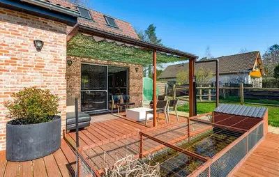 a wooden deck with glass doors and a patio at Beautiful Home In Arendonk With Sauna in Arendonk