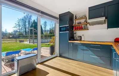 a kitchen with blue cabinets and a large sliding glass door at Beautiful Home In Arendonk With Sauna in Arendonk