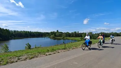 three people riding bikes down a road next to a lake at Klik Klak Studio in Bornem