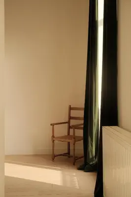 a wooden chair sitting in a room with a window at Maison Gustave in Ghent