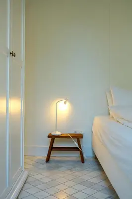 a lamp on a table next to a bed at Maison Gustave in Ghent