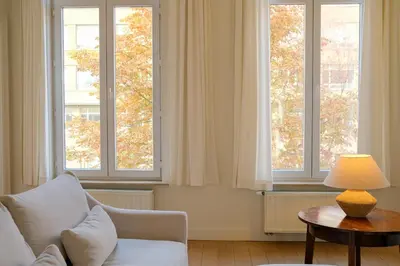 a living room with a couch and two windows at Maison Gustave in Ghent