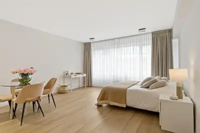 a white bedroom with a bed and a table and chairs at Apartment in the center of Antwerp in Antwerp