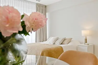 a bedroom with a bed and a vase of pink flowers at Apartment in the center of Antwerp in Antwerp