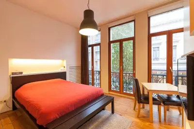 a bedroom with a bed and a table and windows at tam tam city lodge in Antwerp