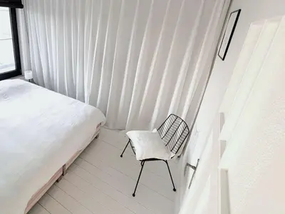 a bedroom with a bed and a chair next to a window at Libertypenthouseghent - Monthly Stays - Miljoenenkwartier Gent in Ghent