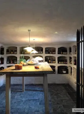a kitchen with a table and shelves with wine bottles at Beautiful 19th-century house in the countryside in Glabbeek