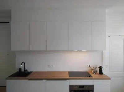 a kitchen with white cabinets and a wooden counter top at NiceFlatInTheStad in Antwerp