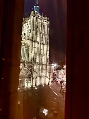 a large building with a clock tower at night at Luxury Rooms by Rikas Hotels in Antwerp