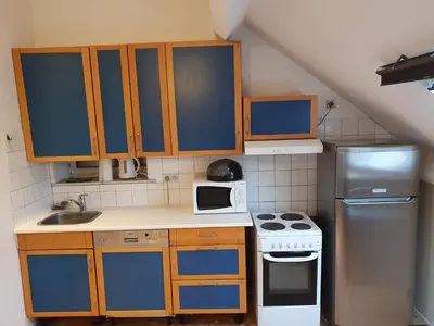a small kitchen with blue cabinets and a refrigerator at Studio meublé in Zaventem