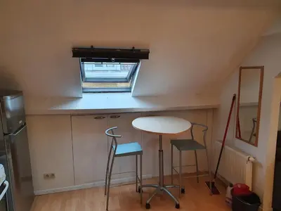 a small kitchen with a table and two stools at Studio meublé in Zaventem