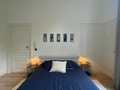 a blue bed in a white room with two tables at Canopée guesthouse in Brussels