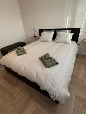 a large white bed with two green towels on it at Parus major in Londerzeel